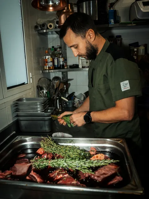 Un chef dresse des herbes sur une pièce de viande